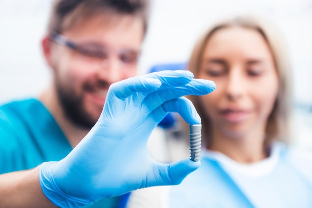 Dentysta pokazujący pacjentowi szary model implantu