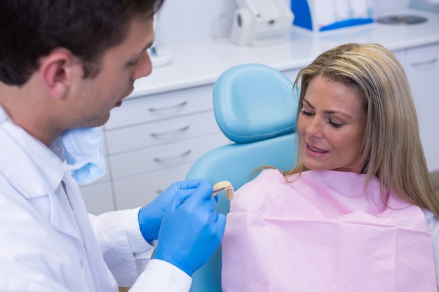 Dentysta pokazuje pacjentowi protezy