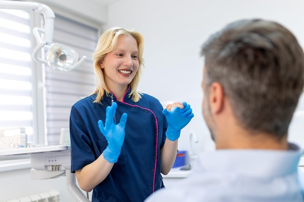 Zdjęcie dentysta przedstawiający pacjentowi formę gipsu dentystycznego lekarz dentysta przedstawiający model szczęki w klinice dentystycznej koncepcja opieki stomatologicznej koncepcja opieki stomatologicznej