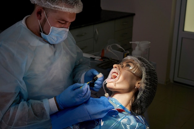 Dentysta robi leczenie stomatologiczne pacjentce. Stomatolog badający zęby pacjenta w sposób nowoczesny
