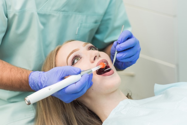 Dentysta robi procedurę z stomatologicznym leczącym światłem UV w klinice