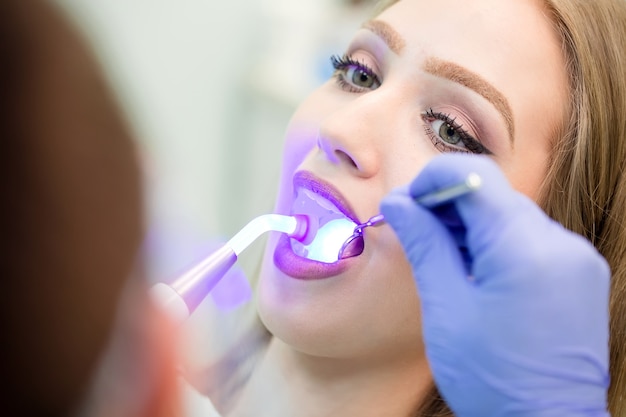 Dentysta robi procedurę z stomatologicznym leczącym światłem UV w klinice