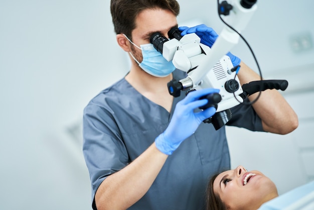 dentysta sprawdzający zęby pacjenta pod mikroskopem w gabinecie chirurgicznym