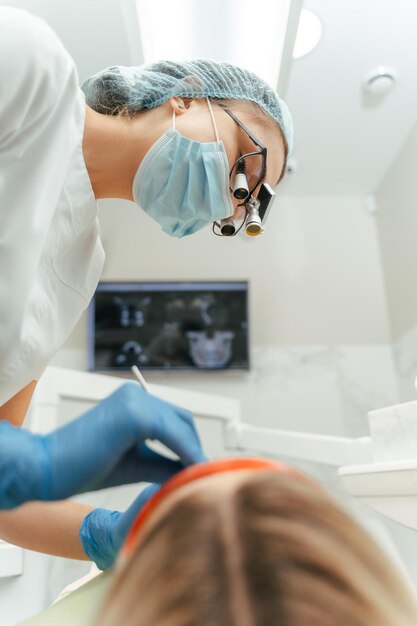 Zdjęcie dentysta trzymający sprzęt podczas badania jamy ustnej pacjentki w klinice stomatologicznej zdrowie zębów