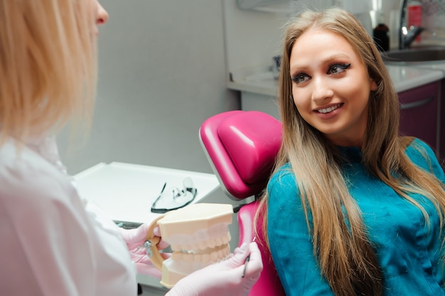 Dentysta w gabinecie stomatologicznym rozmawia z pacjentem i przygotowuje się do leczenia