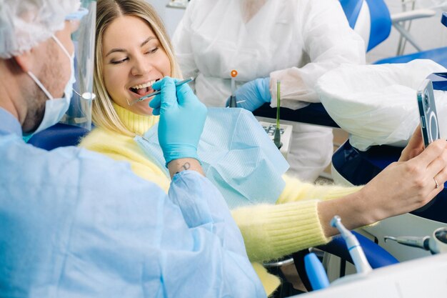 Dentysta w masce ochronnej siedzi obok pacjenta i podczas pracy robi sobie zdjęcie selfie