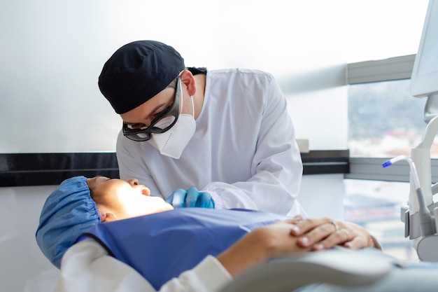 Dentysta w mundurze i masce na twarz podczas interwencji stomatologicznej u pacjenta Koncepcja kliniki stomatologicznej