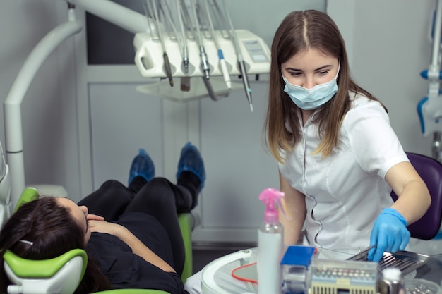 Dentysta w pracy przygotowującej instrumenty do badania zębów kobiety w gabinecie stomatologicznym