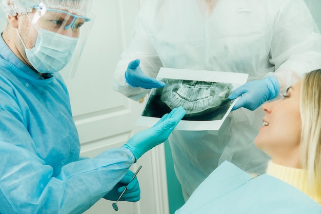 Dentysta wyjaśniający pacjentowi szczegóły prześwietlenia w gabinecie