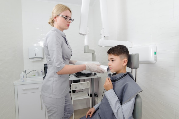 Dentysta wykonuje zdjęcie rentgenowskie szczęki dla małego chłopca w klinice dentystycznej