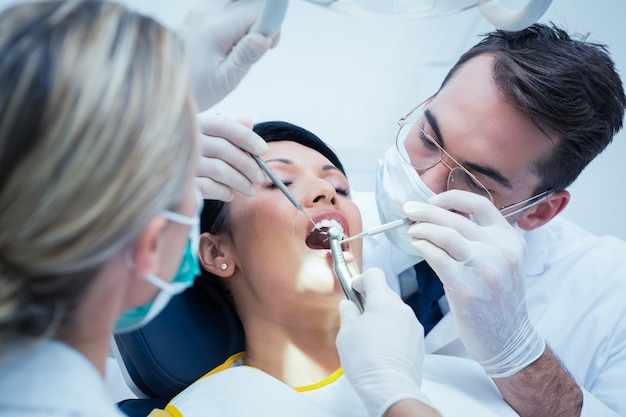 Dentysta z asystentem bada zęby womans