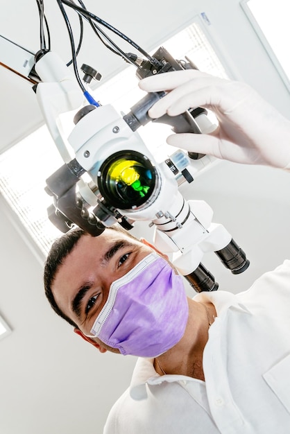 Dentysta z mikroskopem w klinice dentystycznej Lekarz trzymający mikroskop od dołu