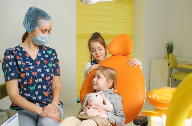 Dentystka uspokaja małą dziewczynkę przed rozpoczęciem leczenia Dziecko przytula ulubioną zabawkę