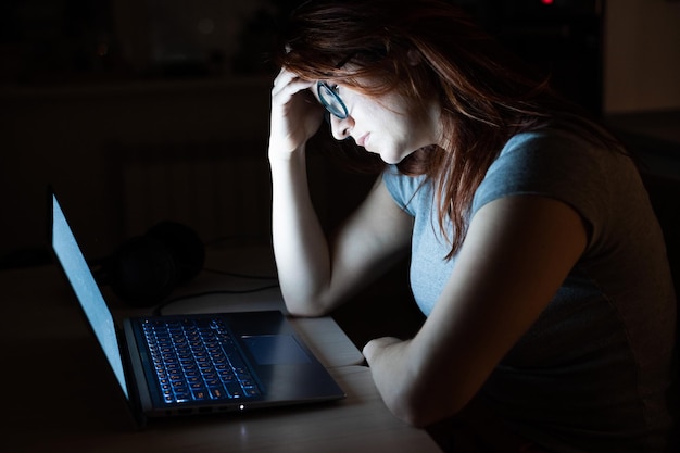 Depresyjna kobieta z laptopem w domu.