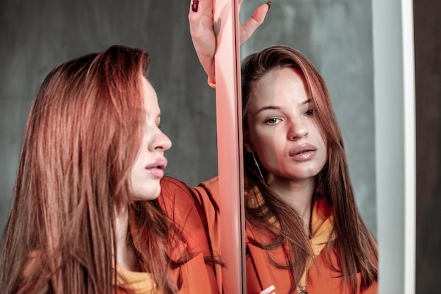 Zdjęcie depresyjny nastrój. ładna dziewczyna stojąca w pozycji pół i patrząc w lustro