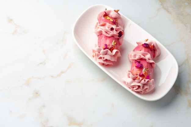 Zdjęcie deser eclair z różowym lukrem na białym stole