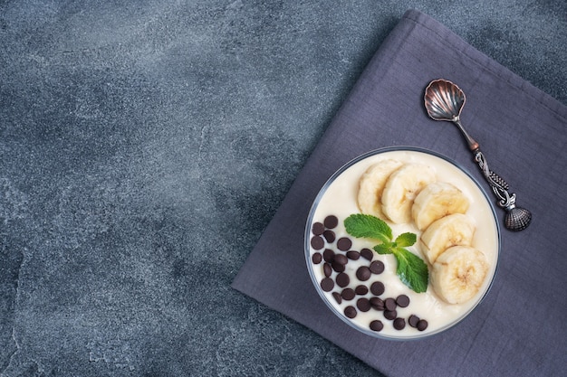 Deser Z Mlekiem, Jogurtem, Bananem I Czekoladą Na ściereczce Kuchennej Na Ciemnoniebieskim Tle