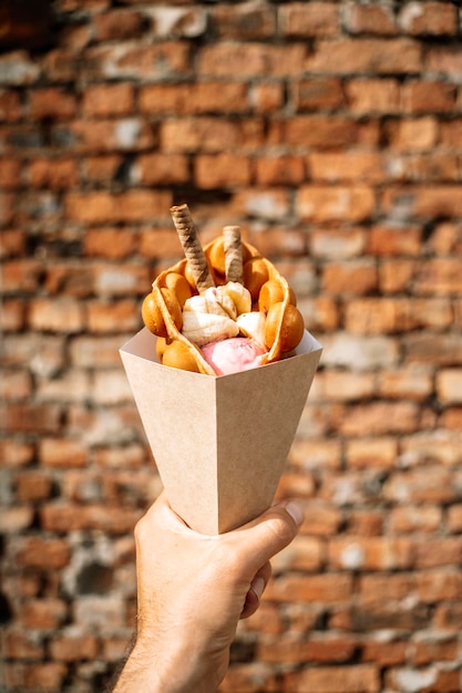 Deser z ulicznego jedzenia Belgijskie wafle w ręku na kolorowym tle ściany Słodycze z ulicy