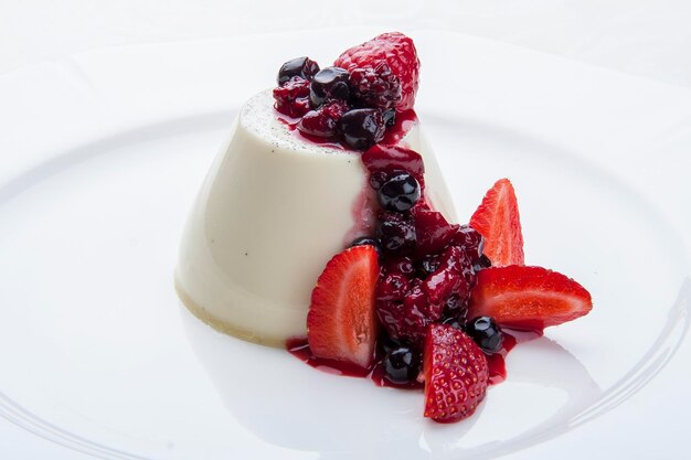 Deserowa panna cotta ze świeżymi jagodami na białym tle