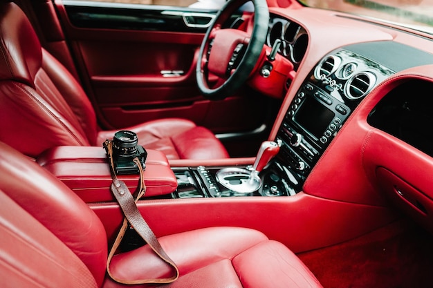 Zdjęcie deska rozdzielcza wnętrza czerwonego luksusowego samochodu ze wskaźnikami kierownica i dźwignia zmiany biegów nowoczesne wnętrze samochodu wygodne skórzane czerwone fotele szczegóły kamera w samochodzie