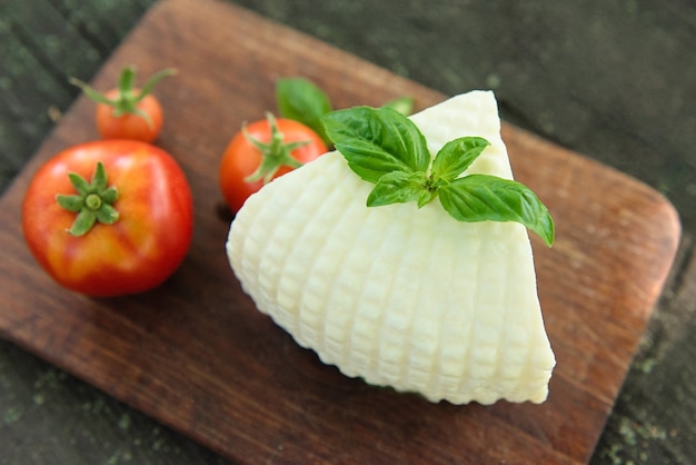 Deska z serem mozzarella, pomidorem i bazylią na ciemnym tle