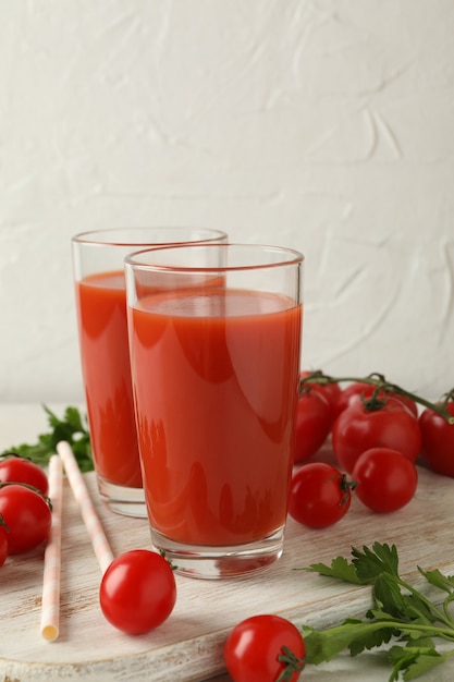 Deska z sokiem pomidorowym i pomidorami na białym teksturą
