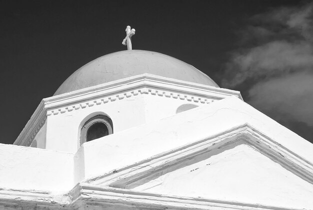 Detal budynku kościoła Mykonos Grecja Kaplica z krzyżem na niebieskiej kopule z ładną architekturą Kościół Agios Nikolaos na słonecznym niebie Letnie wakacje na śródziemnomorskiej wyspie Wanderlust i podróże