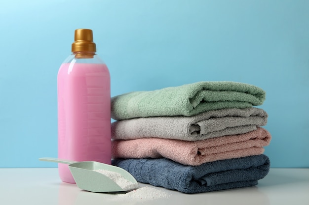 Detergent, miarka z proszkiem i ręczniki na białym stole na niebieskim tle
