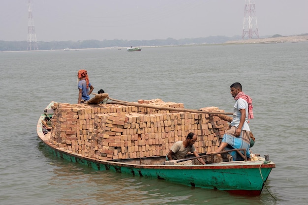 Dhaka Bangladesz march122023 Robotnicy transportujący cegły statkiem wodnym na rzece Transport małych drewnianych trawlerów Drewniana łódź z Azji Południowo-Wschodniej z ładunkiem cegieł