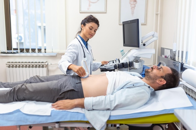 Diagnostyka USG żołądka na jamie brzusznej mężczyzny w klinice widok z bliska Lekarz prowadzi czujnik USG nad brzuchem pacjenta Diagnostyka narządów wewnętrznych