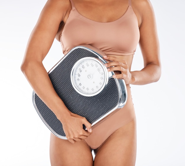 Dieta zdrowotna i pielęgnacja ciała kobieta z postępem odchudzania w skali z treningiem i zdrowym stylem życia Odżywianie fitness i model dopasowania odnowy biologicznej w bieliźnie na białym tle na białym tle w studio