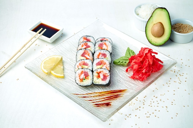 Dietetyczna rolka sushi z twarogiem, tuńczykiem, krewetkami i łososiem na białym talerzu w kompozycji ze składnikami