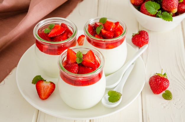 Dietetyczny kremowy jogurtowy panna cotta ze świeżym sosem truskawkowym w szklanych słoikach