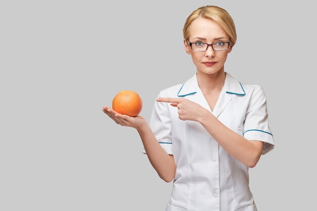 dietetyk lekarz pojęcie zdrowego stylu życia - trzymając organicznych grejpfrutów lub pomarańczy