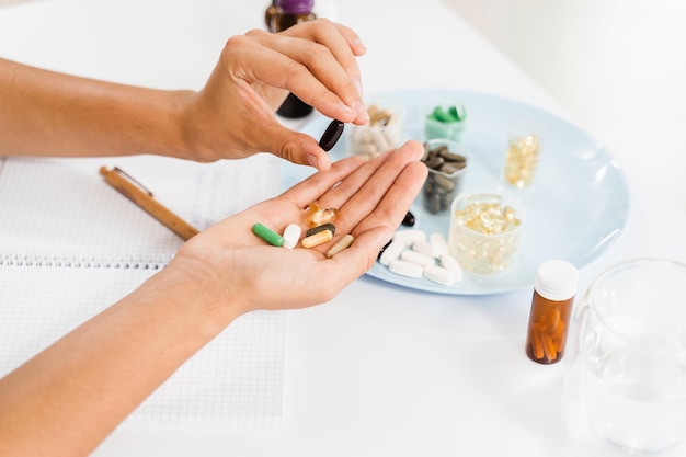 Dietetyk trzyma w dłoniach różne pigułki suplementów diety i pisze receptę na codzienne przyjmowanie tabletek dla klienta w celu opieki zdrowotnej