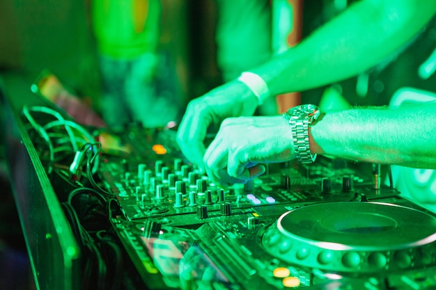 DJ grający muzykę w mikserze na kolorowe niewyraźne tło. Ręce się zamykają