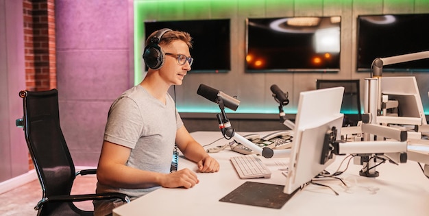 DJ prowadzi program i komunikuje się z publicznością na antenie stacji radiowej Prezenter czyta wiadomości Mężczyzna radiowy mówi do mikrofonu i nagrywa podcast