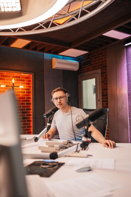 DJ prowadzi program i komunikuje się z publicznością na antenie stacji radiowej Prezenter czyta wiadomości Mężczyzna radiowy mówi do mikrofonu i nagrywa podcast