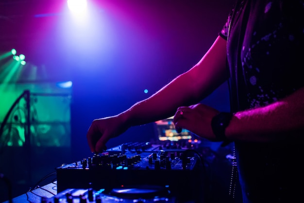 DJ w klubie nocnym grający w profesjonalnym mikserze, zmieniające kolory reflektory