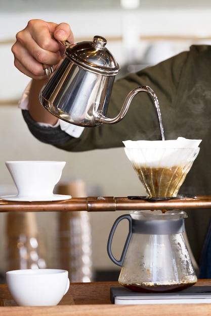 Zdjęcie dłoń trzymająca garnek, wlewając gorącą wodę do kapiącej kawy