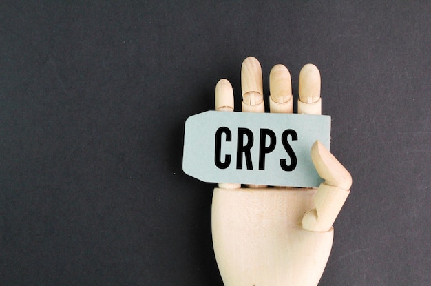 Dłoń trzymająca kartkę z napisem crpsCRPS lub słowo złożony zespół bólu regionalnego