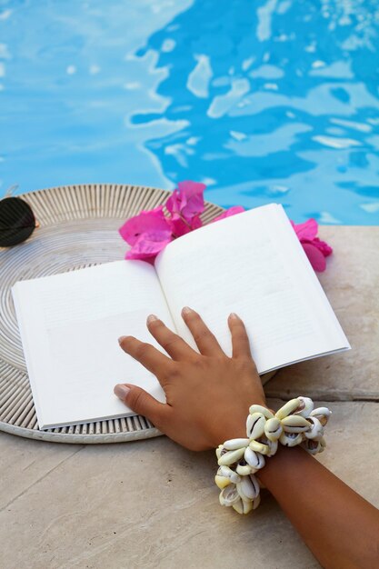 Dłoń trzymająca książkę z kwiatem na plaży piękna kobieta czyta książkę przy basenie przeznaczone do walki radioelektronicznej Pusta książka