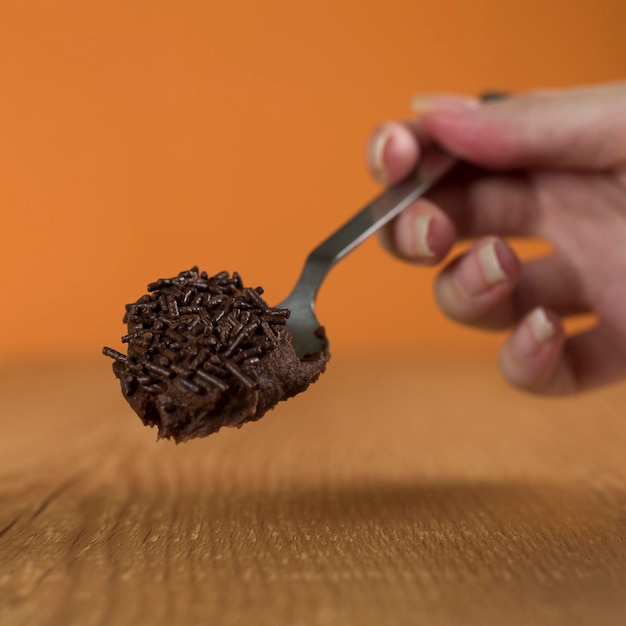 Dłoń trzymająca łyżkę brazylijskiej czekolady o nazwie Brigadeiro Vegan version