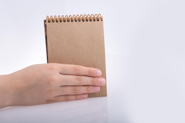 Dłoń trzymająca notatnik w kolorze brązowym