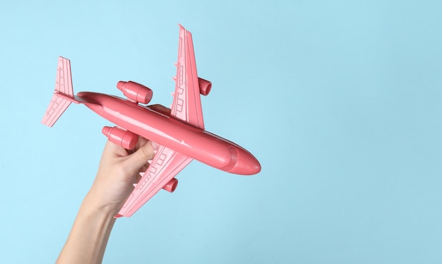 Dłoń trzymająca różowy samolot na niebieskim tle Koncepcja podróży minimalizmu