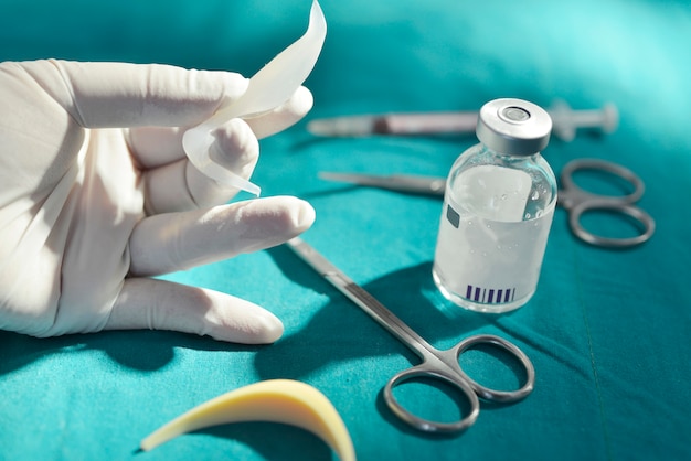 Dłoń Trzymająca Silikonowy Implant Nosowy W Sali Operacyjnej Ze Sprzętem Chirurgicznym