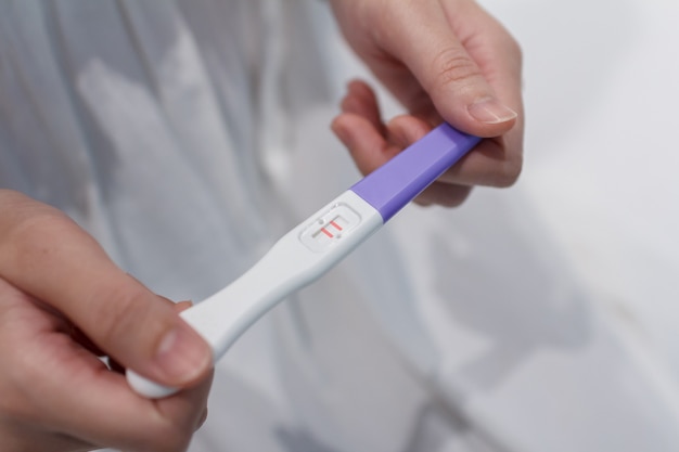 Dłoń trzymająca test ciążowy pokazuje pozytywny wynik.