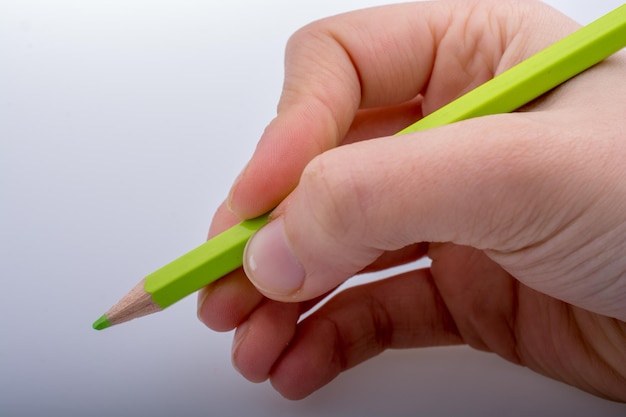 Dłoń trzymająca zielony kolor ołówka na białym tle