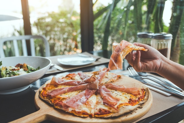 Dłoń Zrywająca Kawałek Pizzy Z Szynką Parmeńską Do Jedzenia W Restauracji