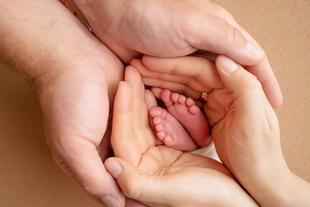 Dłonie rodziców Ojciec i matka trzymają stopy noworodka Stopy noworodka w rękach rodziców Zdjęcie stóp i stóp